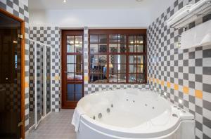 考纳斯道济达斯老城酒店的浴室内设有一个大型白色浴缸,铺有格子瓷砖