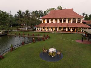 库玛拉孔Taj Kumarakom Resort and Spa Kerala的房屋前方设有桌椅