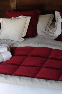 萨奥兹-杜尔克斯伊尔卡普利科诺小木屋酒店的床上的红色和白色棉被和枕头