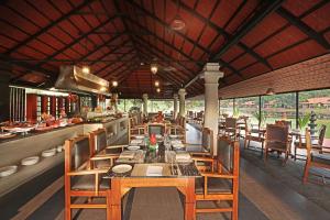 库玛拉孔Taj Kumarakom Resort and Spa Kerala的餐厅配有长桌子和椅子
