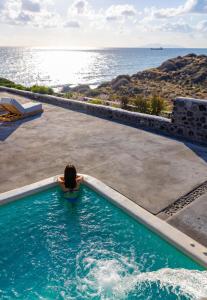 易莫洛林Casa di Mare Luxury Villas的一位在游泳池里看着大海的女人