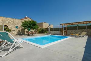 卡米拉日Orelia Cretan Deluxe Apartments的一个带椅子的庭院和房子的游泳池