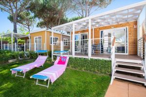 卡斯蒂里昂纳·德拉佩Camping Village Baia Azzurra Club的院子里有粉红色和蓝色长椅的房子