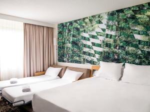 梅里尼亚克Novotel Bordeaux Mérignac的两张位于酒店客房的床,墙上挂着一幅画