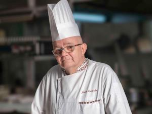 金沙萨金沙萨格兰德铂尔曼酒店的头上戴着厨师帽的人