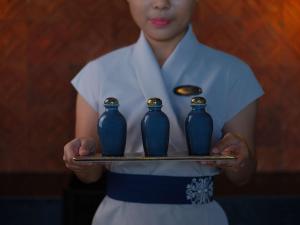 金巴兰Raffles Bali的一位女士拿着一个盘子,上面有三个蓝色花瓶