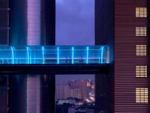 多哈La Cigale Hotel Managed by Accor的夜中城市的蓝桥