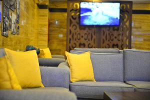 瓦迪穆萨Petra Corner Hotel的客厅设有沙发、黄色枕头和电视