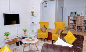 MeruPerfection的客厅配有黄色椅子和沙发