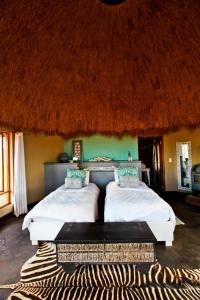 塞斯瑞姆We Kebi Safari Lodge的一间带两张床的卧室和茅草屋顶