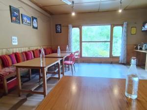 本贾尔Sharda Resort-Tirthan Valley的一间带桌椅的用餐室和窗户。