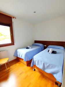 索特Apartaments Sort Pirineus的客房设有两张床、一张桌子和一扇窗户。