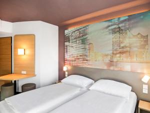 汉堡B&B Hotel Hamburg-Airport的卧室配有一张床,墙上挂有绘画作品