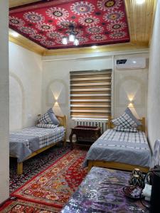 希瓦Khiva Rajab Ota的客房设有两张床和红色天花板。