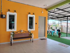 浮罗山背Sri MaLati Homestay and Event Space的黄色的墙壁,设有长凳和庭院