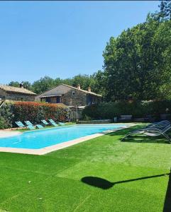尚特梅勒·莱斯·格里格Le Mas des Laurels的庭院中带绿草和椅子的游泳池