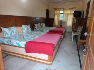 德拉敦Hotel Rajpal Guest House的卧室设有两张单人床和电视。