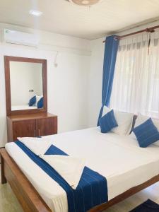 阿努拉德普勒Yatinuwara Bungalow的一间卧室配有一张带蓝白色枕头的大床