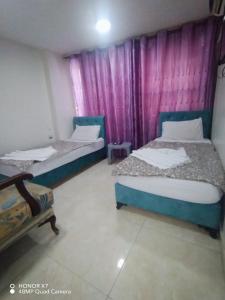 亚喀巴Farah Plaza Hostel &Hotel Apartments的紫色窗帘间内的两张床