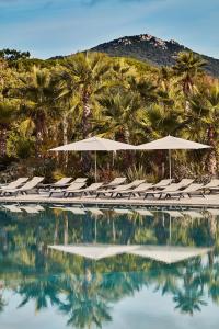 格里莫莱斯德拉梅尔酒店的一个带椅子和遮阳伞的游泳池以及棕榈树