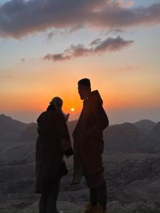 瓦迪穆萨Petra Desert Dream Hotel的日落时分两人站在山顶上
