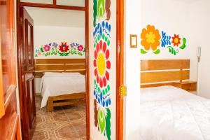 阿亚库乔Hostal Perlaschallay的一间设有一张床的房间和一间墙上花卉的卧室