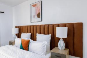 卢萨卡Epignosis Apartments的一张带木制床头板的床和两张台灯