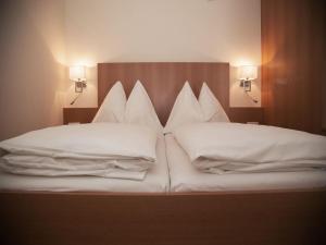 格拉茨克恩布阿姆酒店的一张带白色枕头的床和两盏灯