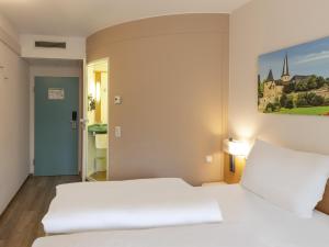 富尔达B&B HOTEL Fulda-Hbf的一间卧室设有两张床,墙上挂着一幅画