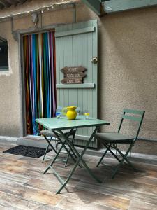 滨海萨纳里Cabanon à Sanary sur mer au coeur de Portissol.的一张绿色桌子和一张靠墙的椅子