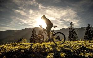 巴特霍夫加施泰因豪斯皮勒酒店的骑着自行车在山里晒太阳的人
