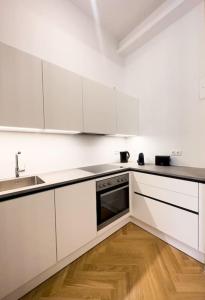 维也纳Exclusive Suite Museumsquartier的白色的厨房配有白色橱柜和木地板