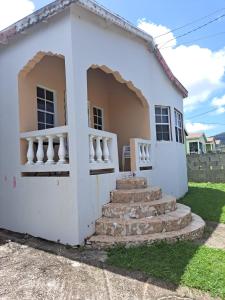 RomneysCozy 2BR/1BA retreat in St.Kitts close to airport的前面有楼梯的白色房子