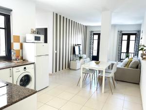 阿雷西费Mahostly Apartamento Comillas PB的厨房以及带白色桌椅的起居室。