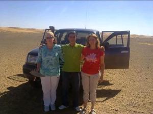 梅尔祖卡GITE Take Ur time的三人站在沙漠中一辆卡车前面