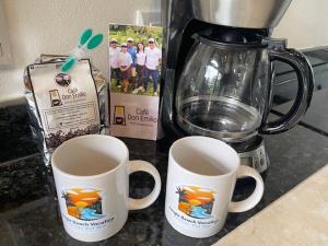 乌维塔Casitas Del Rio Riverfront Jungle Beach Vacation的搅拌机旁的柜台上放两个咖啡杯