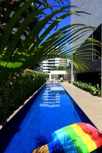 马塞约Porto Kaeté Hotel的一座游泳池,旁边是一座建筑物,上面有一把色彩缤纷的遮阳伞