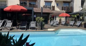 多维尔M大奖Spa酒店 的一座带椅子和遮阳伞的游泳池位于一座建筑旁边
