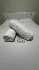 大普拉亚Quintal do forte的床上配有白色毯子和毛巾