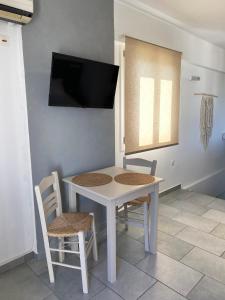 梅加斯·亚洛斯-奈特斯Agnadi Syros Beachfront Studios & Rooms的一张白色的桌子和椅子,墙上配有电视