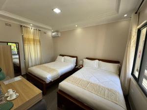 卢萨卡Eleganciana Lodges Limited的小房间设有两张床和一张桌子