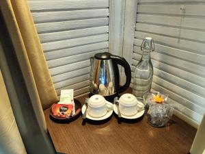 金巴兰Balangan Surf Resort的茶壶、茶杯和一瓶