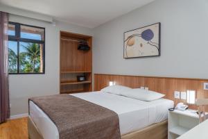 马塞约Ritz Plazamar Hotel的一间卧室配有一张床和一张带电话的书桌