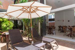 马塞约Ritz Plazamar Hotel的庭院配有两把椅子和一把遮阳伞