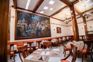 库斯科Hotel Hacienda Cusco Plaza的一间设有桌子的用餐室和墙上的绘画