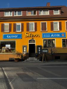 FrickenhausenGasthof Stern Asteri的一座橙色的建筑,旁边标有标志