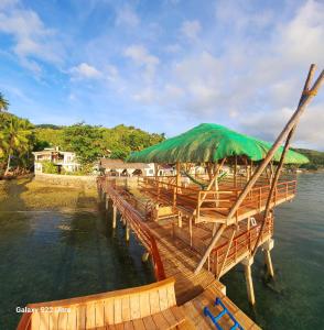 LibagonCHUE&LARRY'S BEACHSIDE HOMESTAY的水边带绿伞的木码头