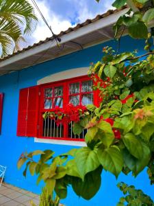 弗洛里亚诺波利斯Pequi hostel的红色的窗户,在蓝色的房屋上,有红色的花