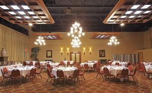 布莱斯维尔布莱斯维尔假日酒店的宴会厅配有白色的桌椅和吊灯