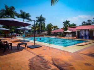 比亚维森西奥Hotel campestre las palmas的度假村内带椅子和遮阳伞的游泳池